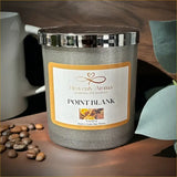 Gray candle with a label on a wooden surface with a mug and stones.