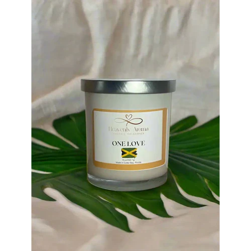 White scented candle in glass jar with One Love label and Jamaican flag for powerful fragrance throw.