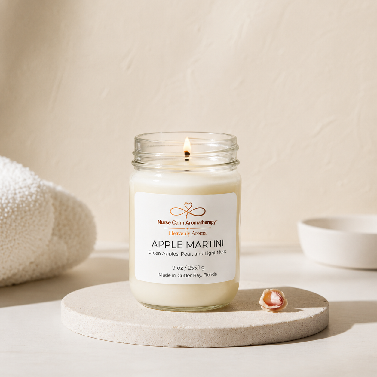 Candle in a glass jar labeled 'Apple Martini' on a neutral background