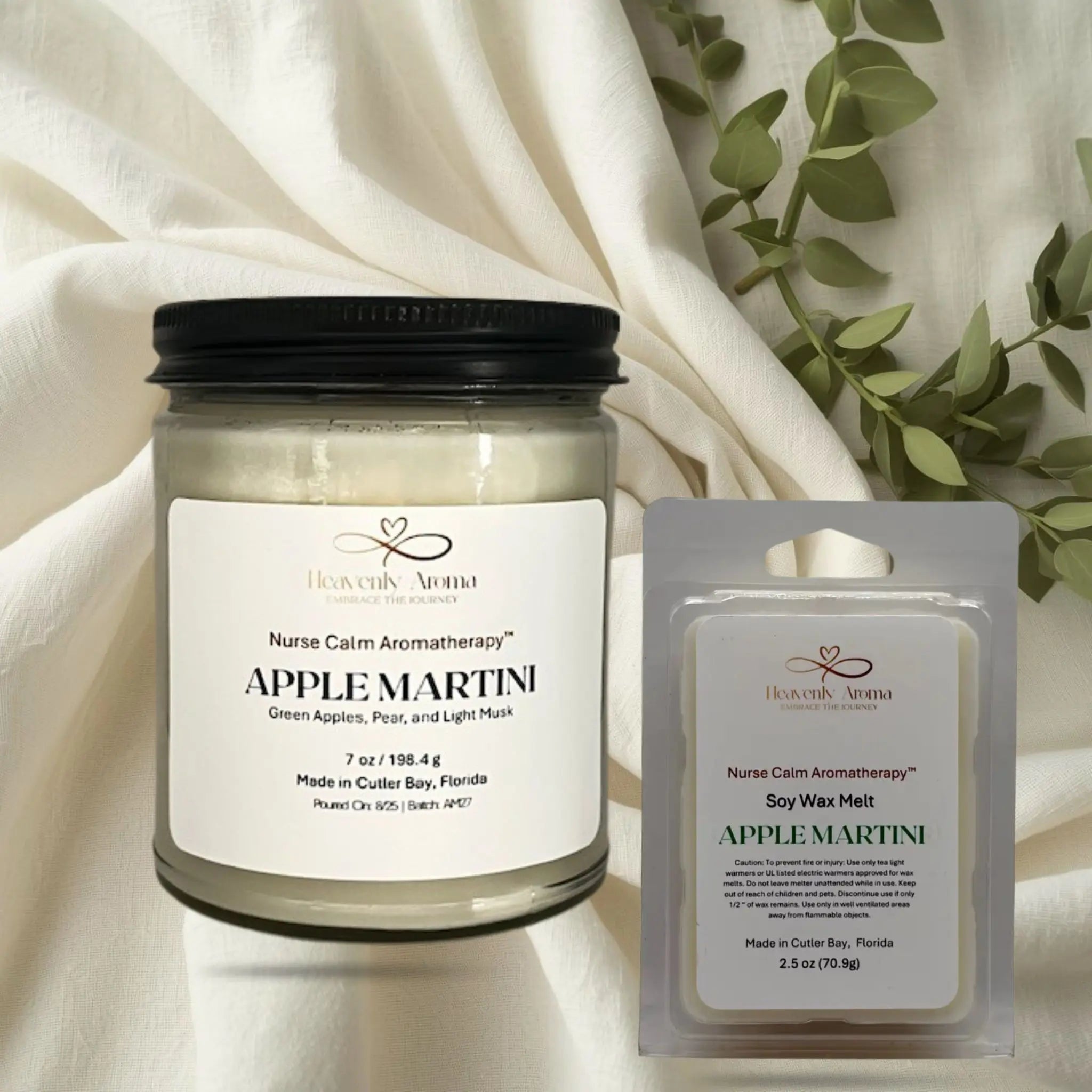 Apple Martini candle and wax melt set on a white fabric background with green leaves.