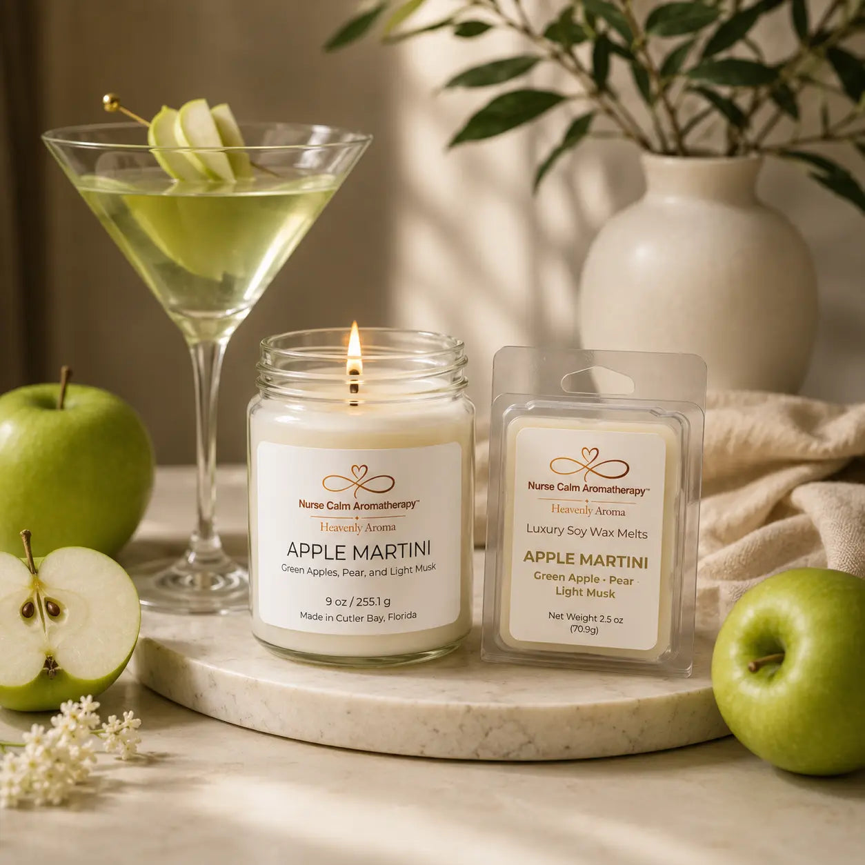 Apple Martini candle and wax melts with a glass of green liquid and apples on a marble surface.