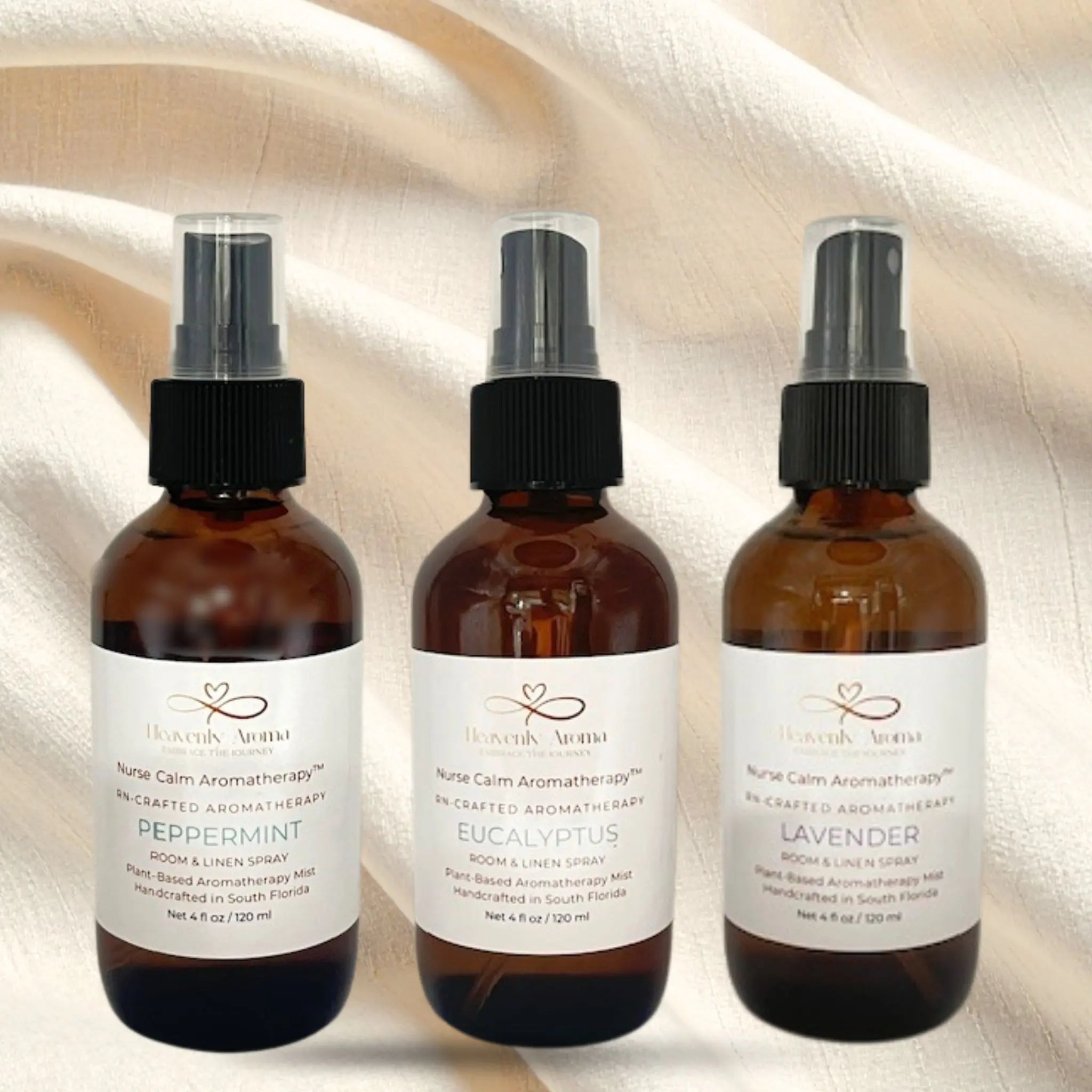 Three amber glass bottles with black spray nozzles on a textured beige background