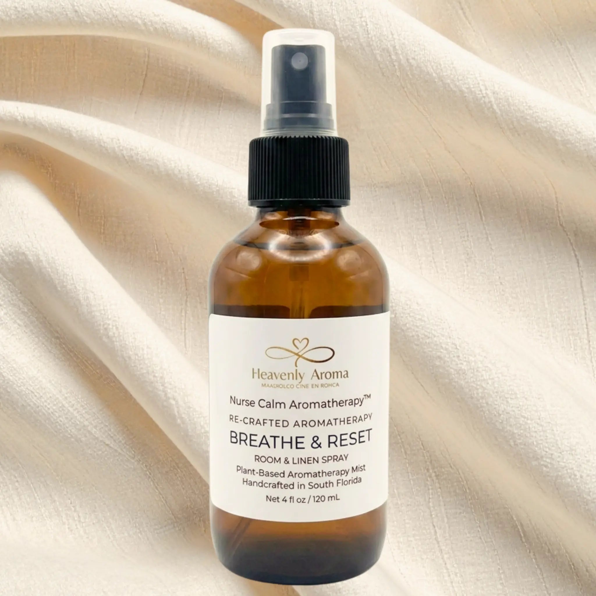 Bottle of Heavenly Aroma 'Breathe & Reset' room and linen spray on a beige fabric background