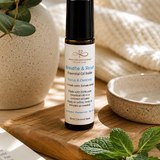 Essential oil roller bottle on a wooden surface with plants and a book in the background