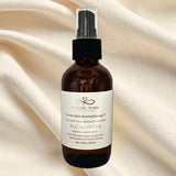Brown glass bottle with black spray nozzle on a beige fabric background