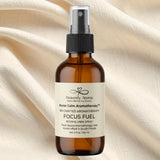 Brown bottle of 'Focus Fuel' aromatherapy spray with a label on a beige fabric background
