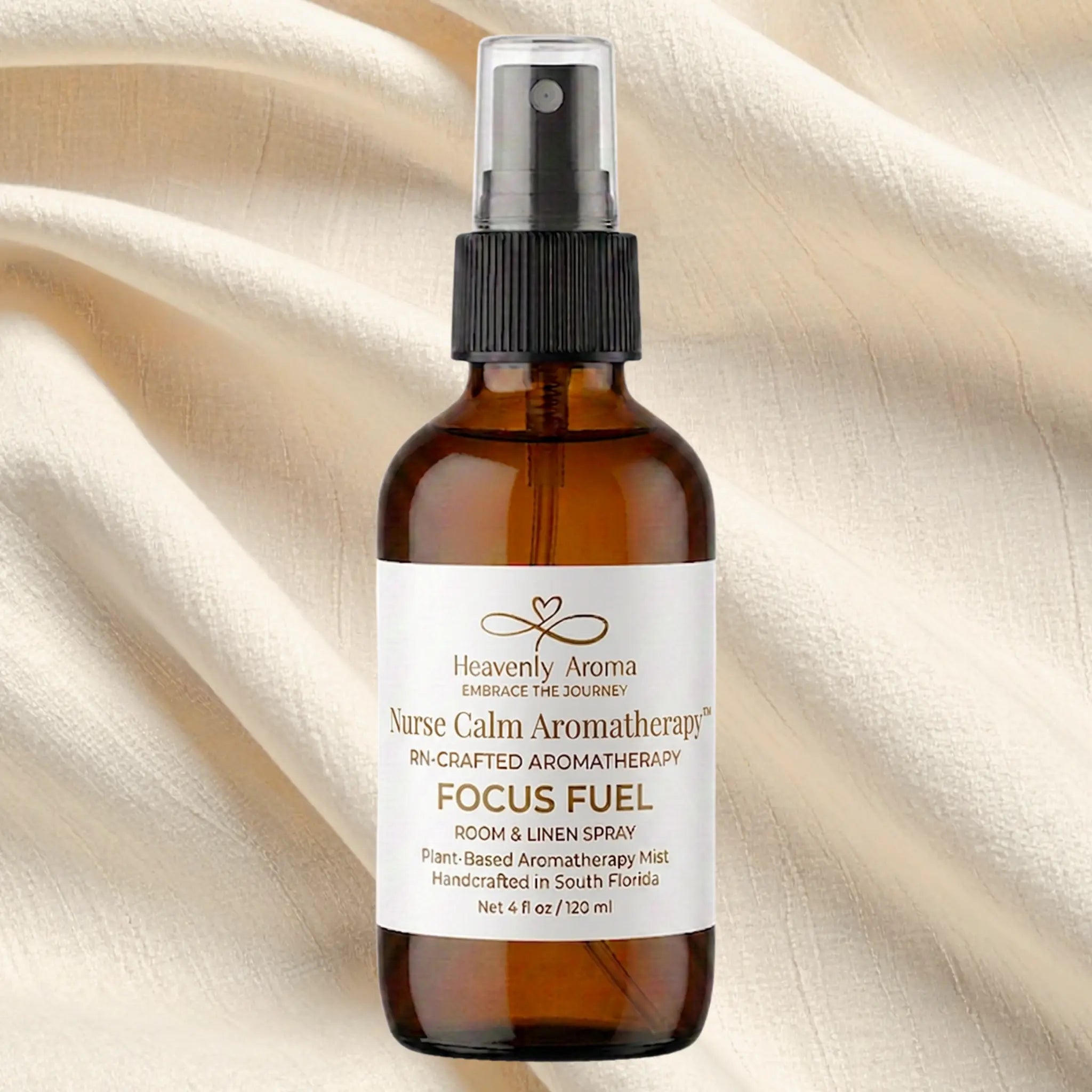 Brown glass bottle with black spray nozzle on a beige fabric background