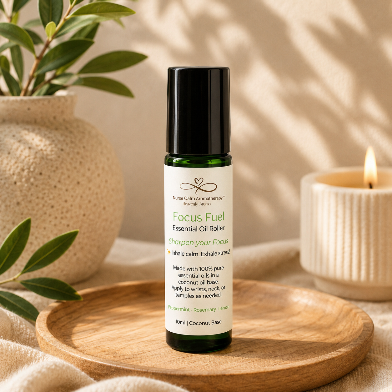 Essential oil roller bottle labeled 'Focus Fuel' on a wooden tray with a candle and plant in the background.