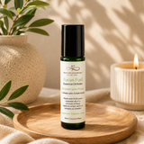 Essential oil roller bottle labeled 'Focus Fuel' on a wooden tray with a candle and plant in the background.