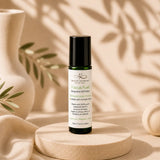 Essential oil roller bottle labeled 'Focus Fuel' on a beige surface with leafy background