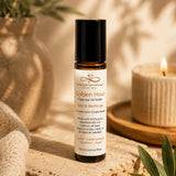 Essential oil roller bottle labeled 'Golden Hour' on a textured surface with plants and a candle in the background.