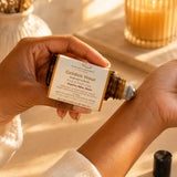 Applying Golden Hour essential oil roller to the wrist as part of a calming self-care ritual.
