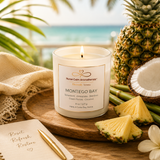 Candle labeled 'Montego Bay' with pineapple, coconut, and bamboo on a wooden surface with a beach background.