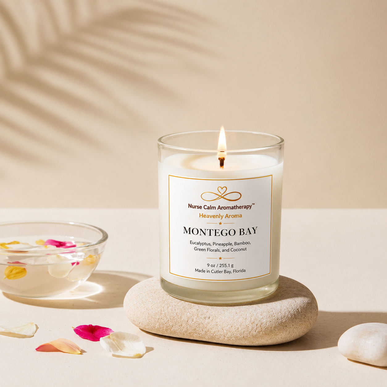Candle labeled 'Montego Bay' on a stone with petals and a bowl in the background