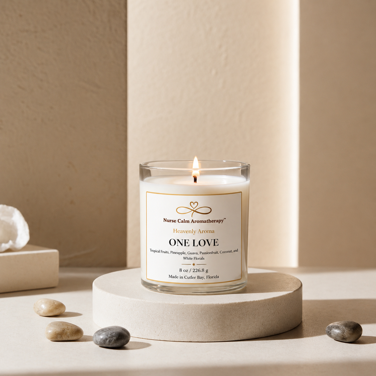 Candle labeled 'One Love' on a beige pedestal with a neutral background