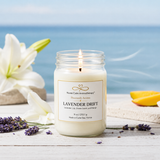 Candle in a jar labeled 'Lavender Drift' with flowers and fruit on a wooden surface.