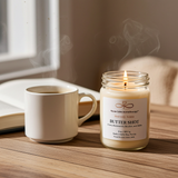 Butter Shot soy candle with a steaming coffee mug creating a warm and relaxing atmosphere.