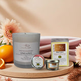 Candle and packaging with 'One Love' branding on a decorative tray with flowers and oranges.