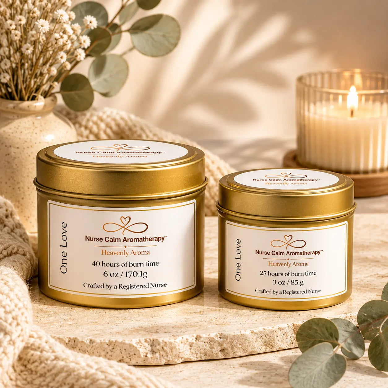 Two candles from Nurse Calm Aromatherapy on a wooden surface with eucalyptus leaves.