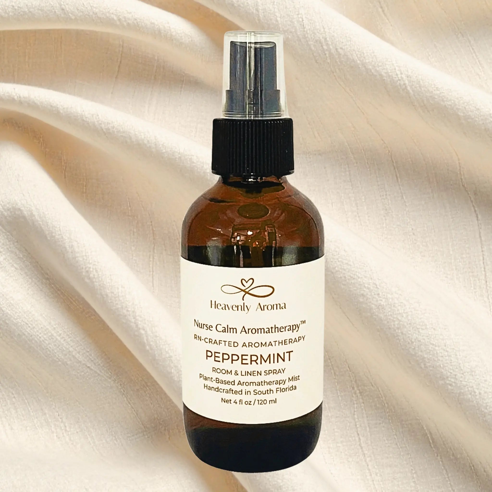 Bottle of Heavenly Aroma peppermint room and linen spray on a beige fabric background