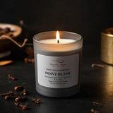 Candle with a label on a dark surface with cloves and other spices.