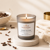 Candle labeled 'Point Blank' from Nurse Calm Aromatherapy on a neutral background with clove spices.