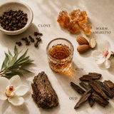 Flat lay featuring cloves, oud wood, warm spices, rum-inspired accents, and rich botanicals representing the Point Blank fragrance profile.