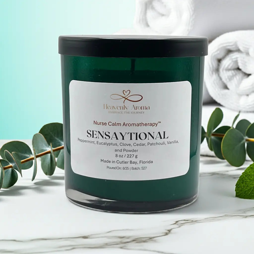 Candle labeled 'Sensaytional' by Heavenly Aroma on a marble surface with eucalyptus leaves.