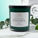 Candle labeled 'Sensaytional' by Heavenly Aroma on a marble surface with eucalyptus leaves.