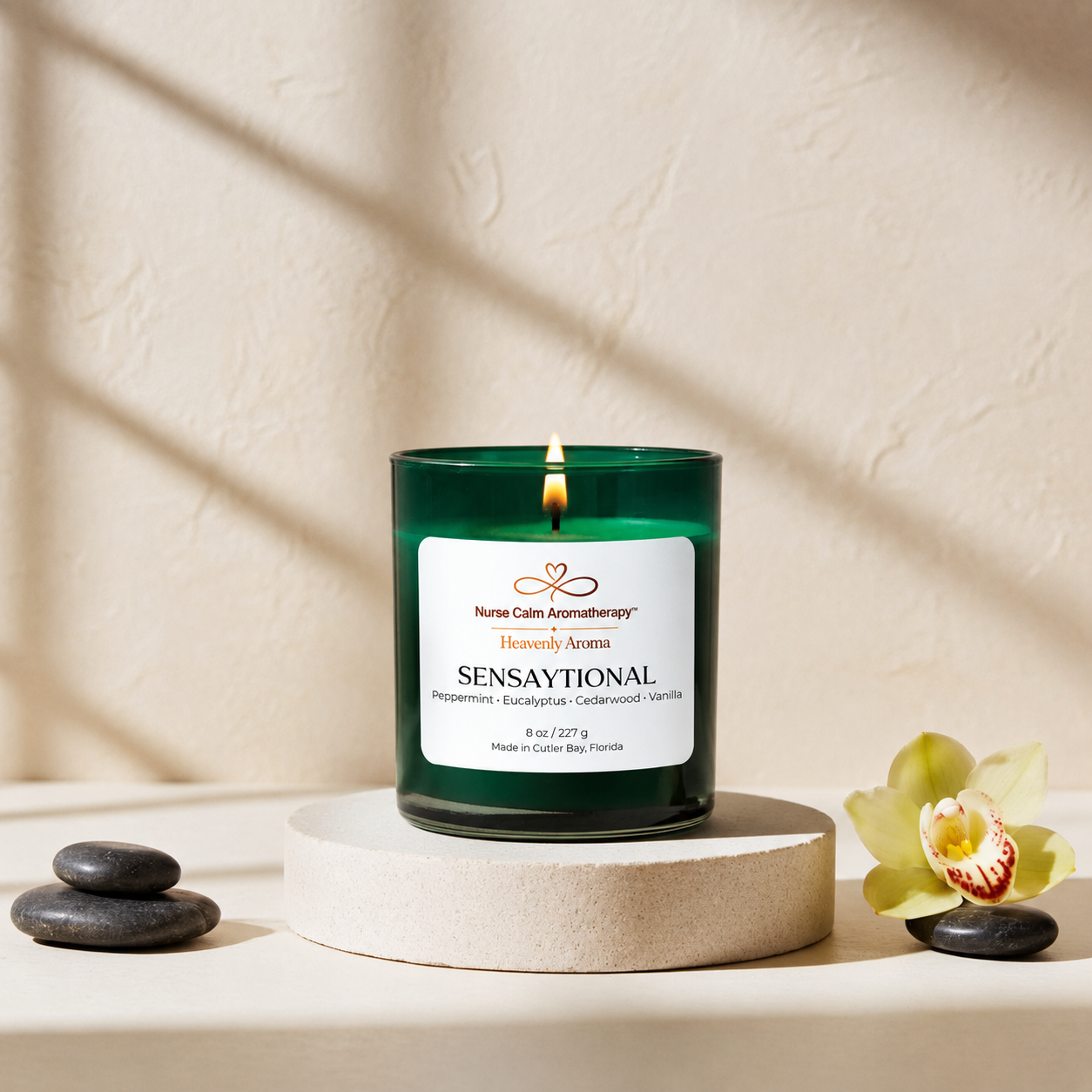 Sensaytional candle on a white surface with a flower and stones