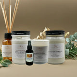 Collection of natural products including candles, diffusers, and a bottle on a beige background