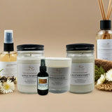 Collection of natural products including candles, diffusers, and sprays on a beige background