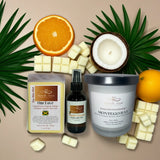 Collection of natural products including a candle, soap, and essential oil on a beige background with palm leaves.