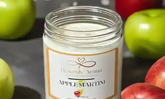 Apple martini scented candle in a clear glass jar with white wax and orange label.