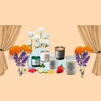 A collection of scented candles in glass jars with varying colors and designs, surrounded by fresh flowers and fruit.