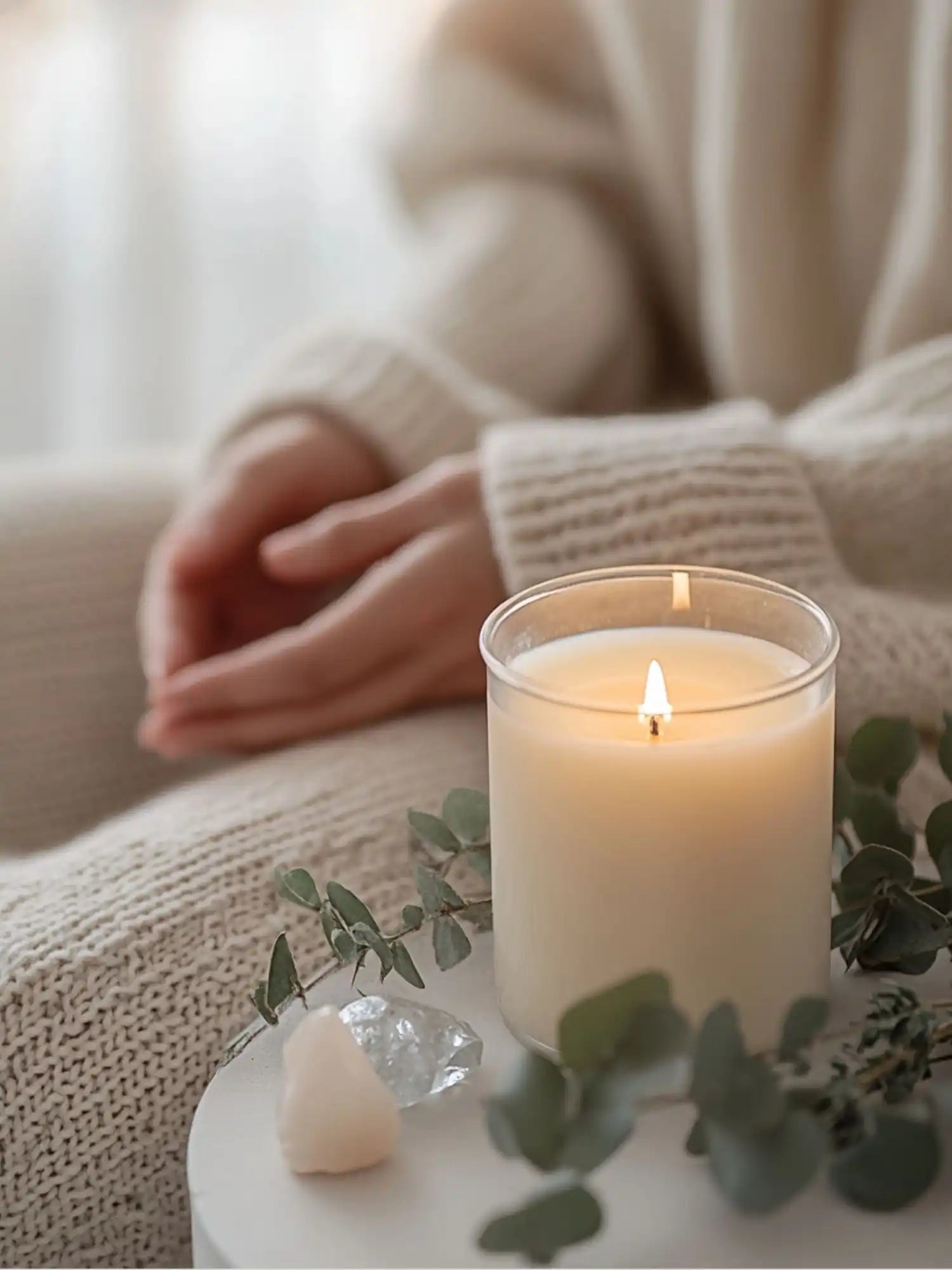 A lit, unscented, off-white pillar candle in a clear glass jar.