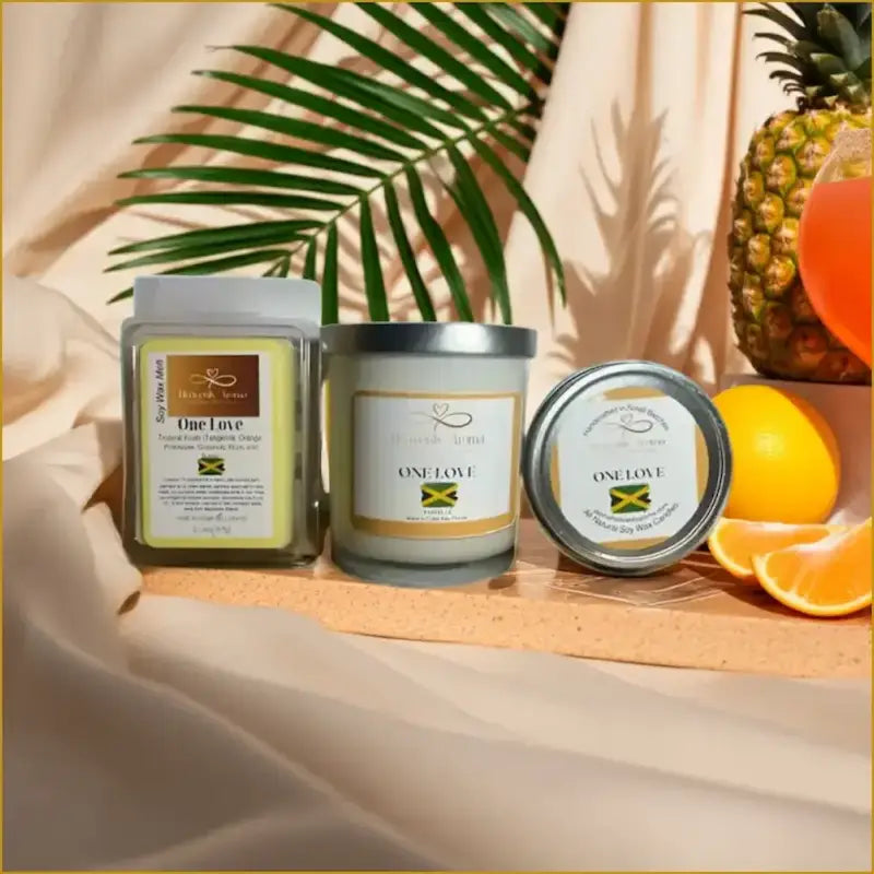Candles with 'One Love' branding on a wooden tray with fruits and leaves.