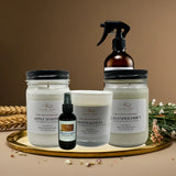 Collection of natural products including candles and sprays on a decorative tray with a brown background.
