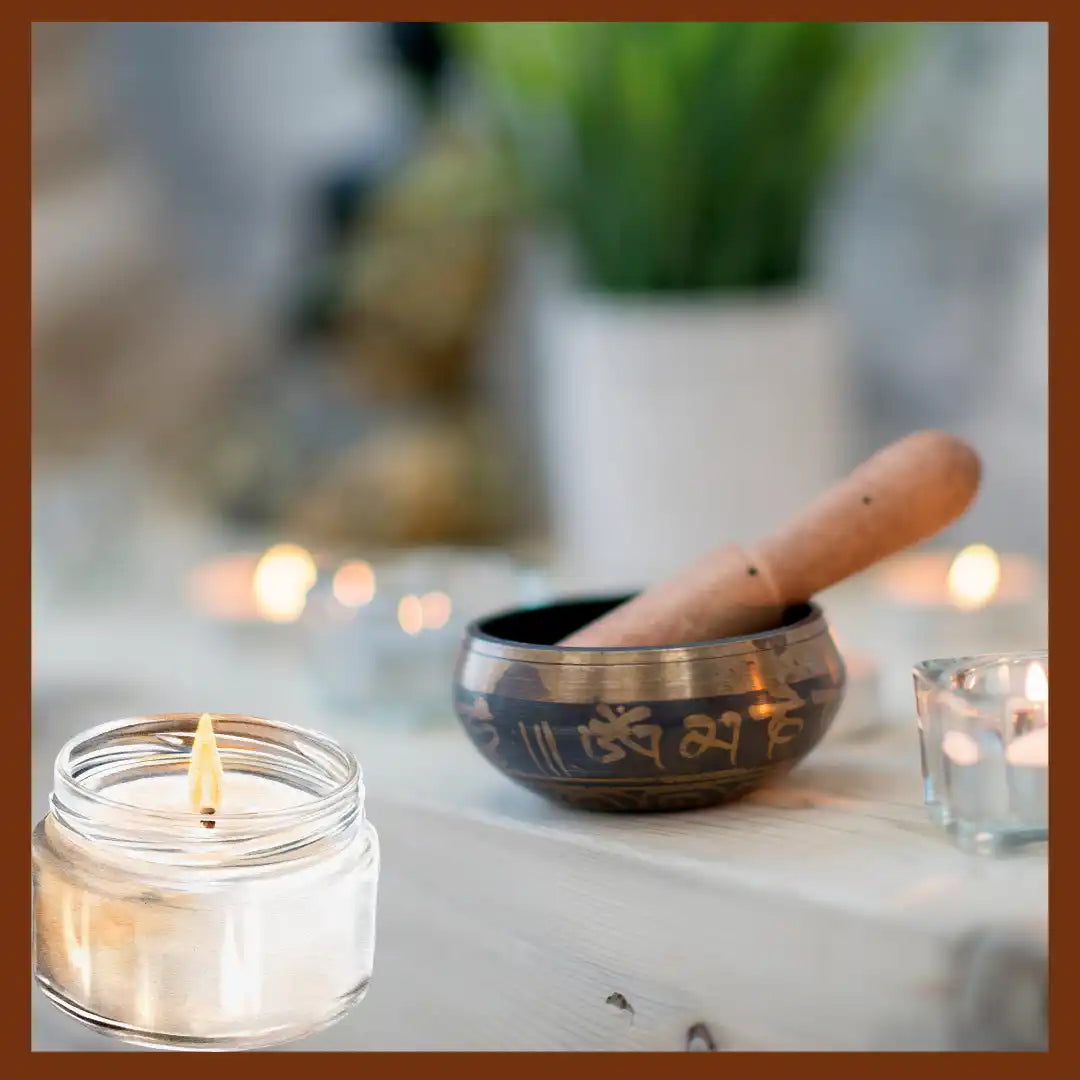 Tibetan singing bowl with a wooden striker beside a lit candle in a jar.